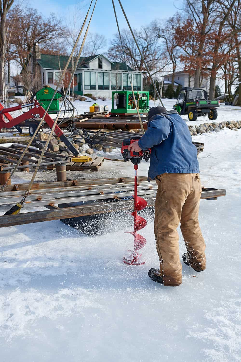 Man drilling into frozen lake
